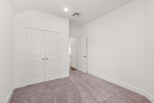 unfurnished bedroom with carpet flooring, vaulted ceiling, and a closet