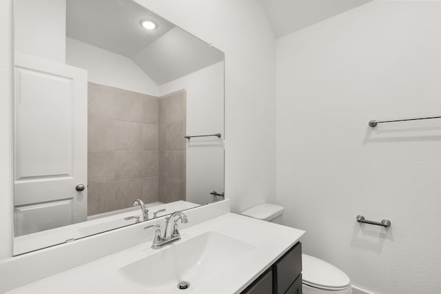 bathroom with vanity, toilet, and lofted ceiling