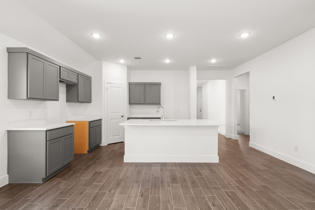 kitchen featuring sink, gray cabinets, dark hardwood / wood-style flooring, and a kitchen island with sink