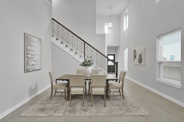 dining room featuring a chandelier, hardwood / wood-style floors, a healthy amount of sunlight, and a high ceiling