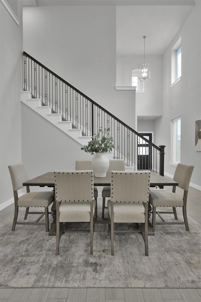 dining area featuring wood-type flooring, a high ceiling, and a notable chandelier