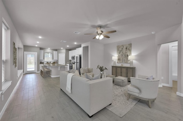 living room with ceiling fan and light hardwood / wood-style floors