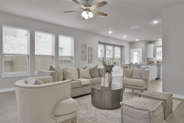 living room featuring sink, light wood-type flooring, a wealth of natural light, and ceiling fan