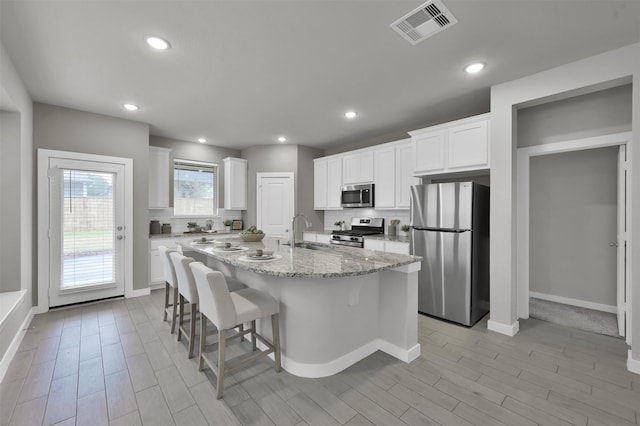 kitchen featuring sink, white cabinetry, a kitchen island with sink, and appliances with stainless steel finishes