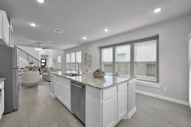 kitchen featuring white cabinets, appliances with stainless steel finishes, a center island with sink, and sink