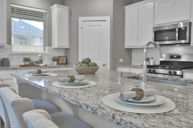 kitchen featuring appliances with stainless steel finishes, tasteful backsplash, and white cabinetry