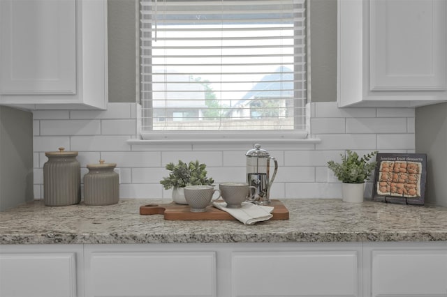 room details with tasteful backsplash, light stone countertops, and white cabinets