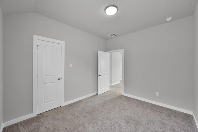 spare room with light colored carpet and vaulted ceiling