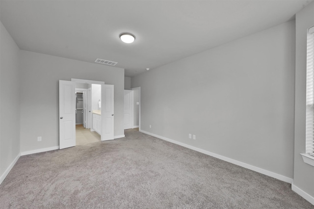 unfurnished bedroom featuring a walk in closet and light carpet