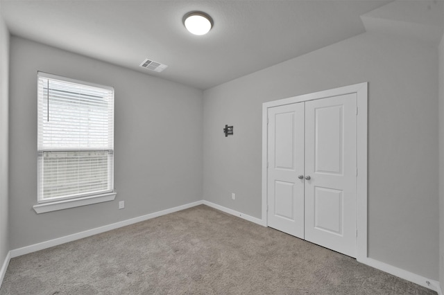 unfurnished bedroom with lofted ceiling, light carpet, and a closet