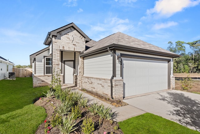 view of front of home featuring central AC unit, a front yard, and a garage