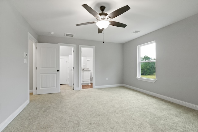 unfurnished bedroom with ceiling fan, light carpet, and ensuite bath