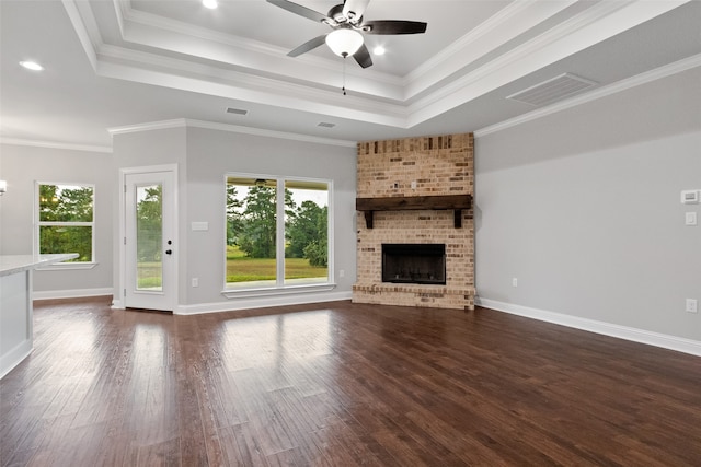 unfurnished living room with a brick fireplace, ceiling fan, dark hardwood / wood-style floors, and ornamental molding