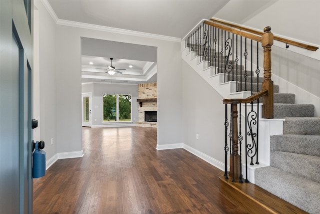 foyer entrance featuring ceiling fan, dark hardwood / wood-style flooring, ornamental molding, and a brick fireplace