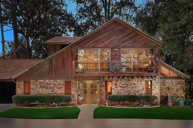 view of front of home with a front lawn, a balcony, and french doors