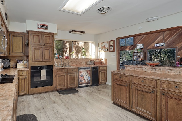 kitchen featuring sink, tasteful backsplash, light hardwood / wood-style flooring, and black appliances