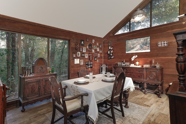 dining area with hardwood / wood-style floors, a healthy amount of sunlight, and wood walls