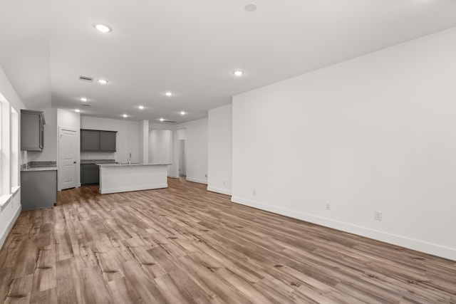 unfurnished living room featuring hardwood / wood-style flooring and sink