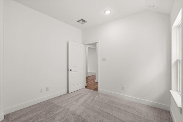 carpeted empty room with a wealth of natural light and vaulted ceiling