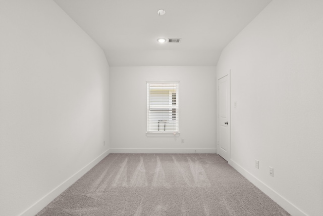 carpeted empty room with lofted ceiling