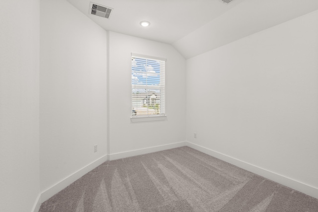 spare room with carpet and vaulted ceiling