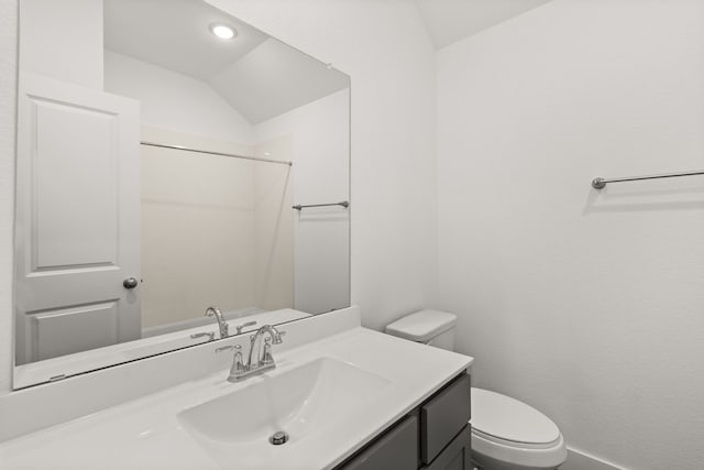 bathroom featuring vanity, toilet, and lofted ceiling