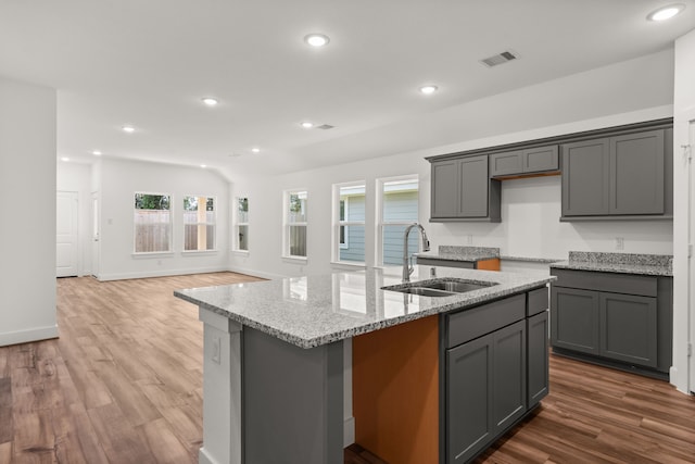 kitchen featuring gray cabinetry, a kitchen island with sink, sink, and hardwood / wood-style floors