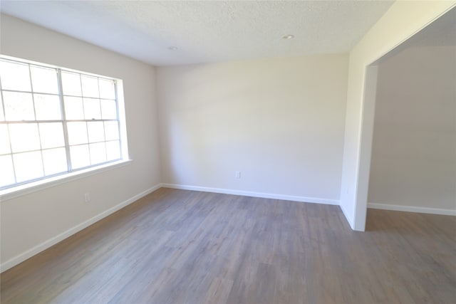 empty room featuring a textured ceiling and dark hardwood / wood-style floors