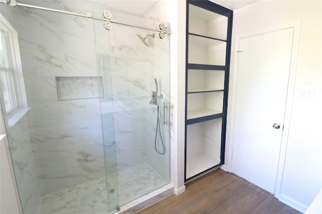 bathroom with hardwood / wood-style flooring and a shower with shower door