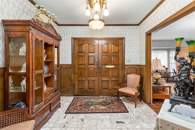 foyer entrance with wooden walls, a notable chandelier, and ornamental molding