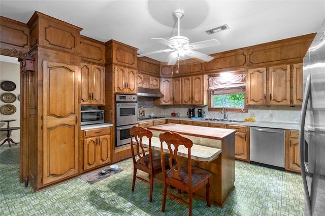 kitchen with decorative backsplash, stainless steel appliances, ceiling fan, and sink