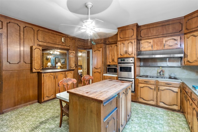 kitchen with a center island, backsplash, ceiling fan, appliances with stainless steel finishes, and butcher block counters