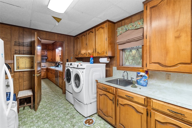 laundry room featuring washer and dryer, wood walls, cabinets, and sink