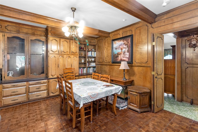 dining space featuring dark parquet floors, wood walls, ornamental molding, and beam ceiling