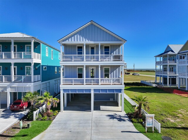 raised beach house with a balcony, a front yard, and a carport