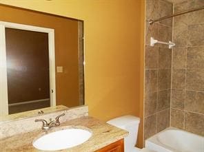 full bathroom with vanity, tiled shower / bath combo, and toilet