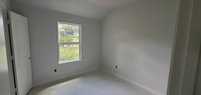 spare room featuring concrete floors and lofted ceiling