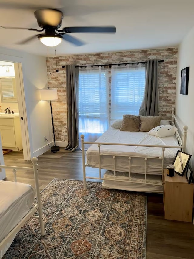 bedroom featuring dark hardwood / wood-style floors, ensuite bath, ceiling fan, and sink