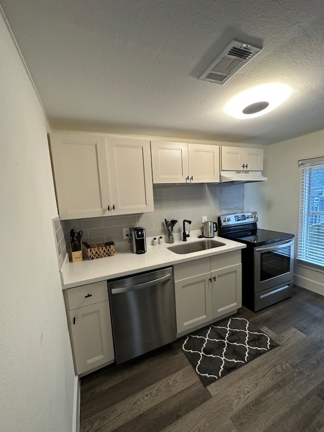 kitchen with white cabinetry, sink, dark wood-type flooring, stainless steel appliances, and backsplash