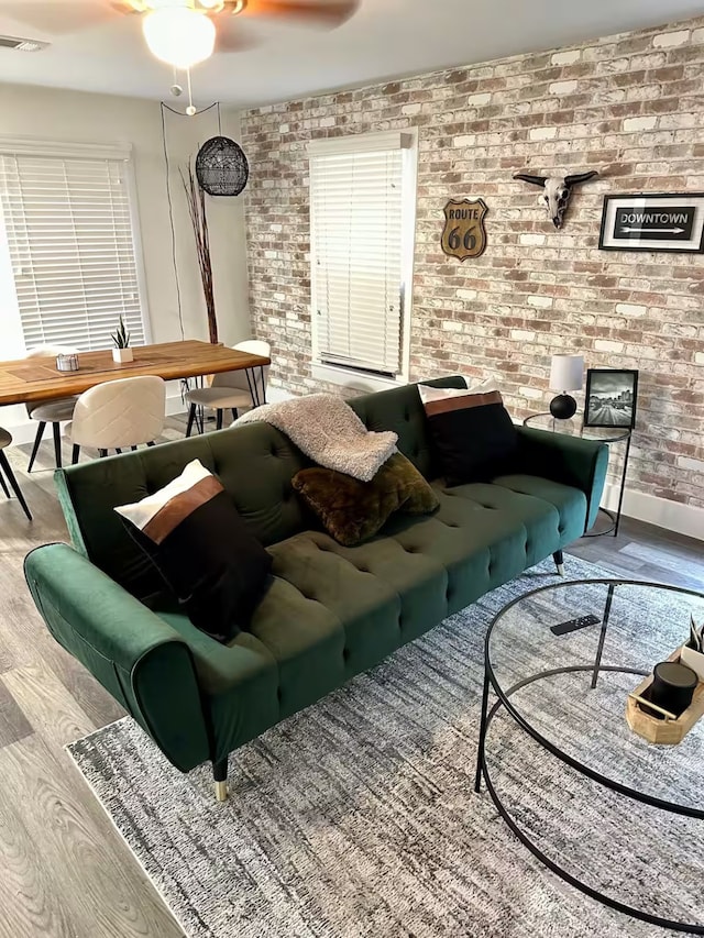 living room featuring ceiling fan, brick wall, and hardwood / wood-style flooring