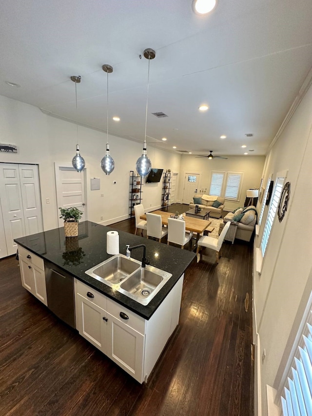 kitchen with pendant lighting, dark wood-type flooring, white cabinets, a center island with sink, and sink