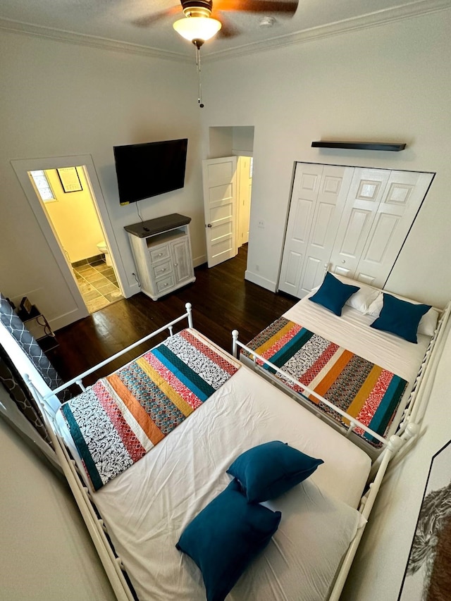 bedroom with a closet, dark hardwood / wood-style floors, ceiling fan, and crown molding