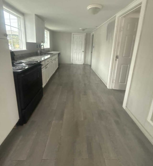 kitchen with white cabinets, black range with electric stovetop, dark wood-type flooring, and sink