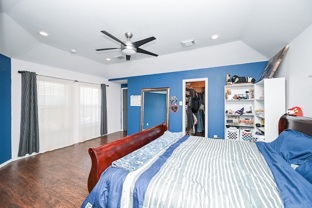 bedroom with a walk in closet, vaulted ceiling, ceiling fan, wood-type flooring, and a closet