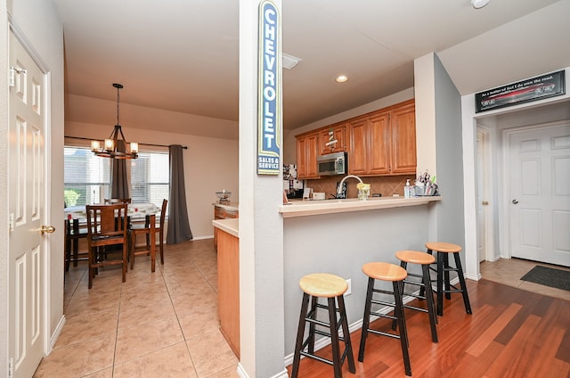 kitchen featuring a kitchen breakfast bar, a notable chandelier, kitchen peninsula, pendant lighting, and light hardwood / wood-style floors