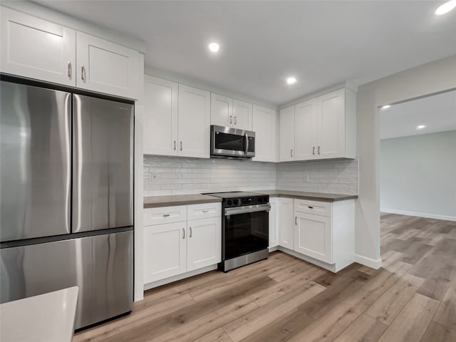 kitchen with appliances with stainless steel finishes, light wood-type flooring, and white cabinetry