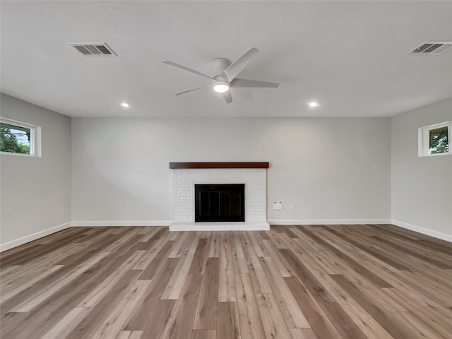 unfurnished living room with a fireplace, light wood-type flooring, and ceiling fan