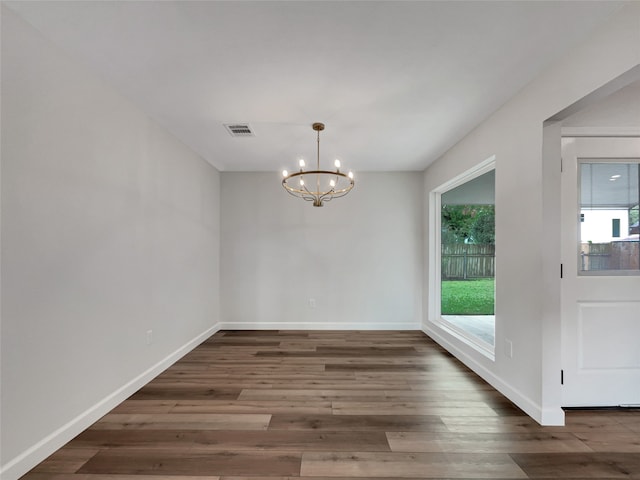 unfurnished dining area featuring a chandelier and dark wood-type flooring