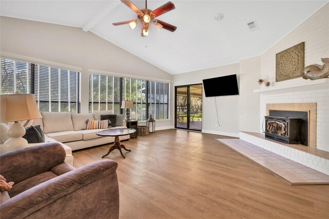 living area with visible vents, beam ceiling, high vaulted ceiling, a ceiling fan, and wood finished floors