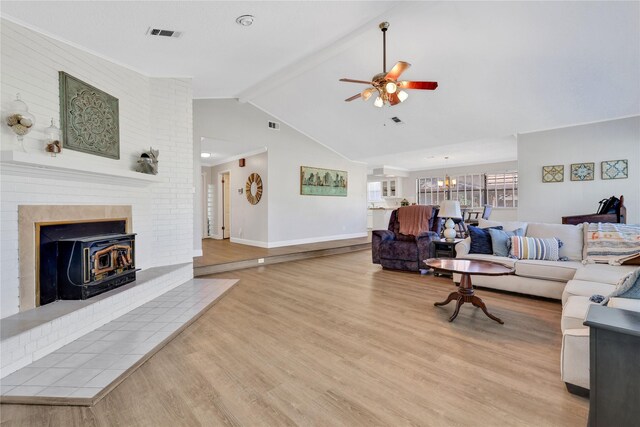 living area with visible vents, light wood-style flooring, ceiling fan with notable chandelier, baseboards, and vaulted ceiling with beams